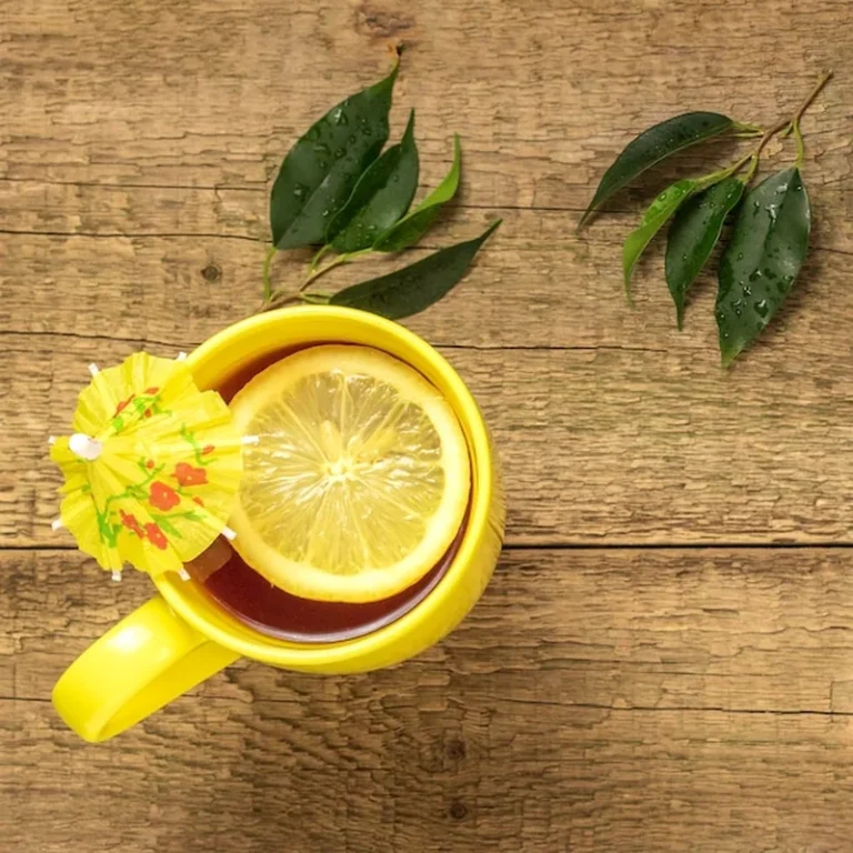 Herbata z cytryną w żółtym kubku na drewnianym tle