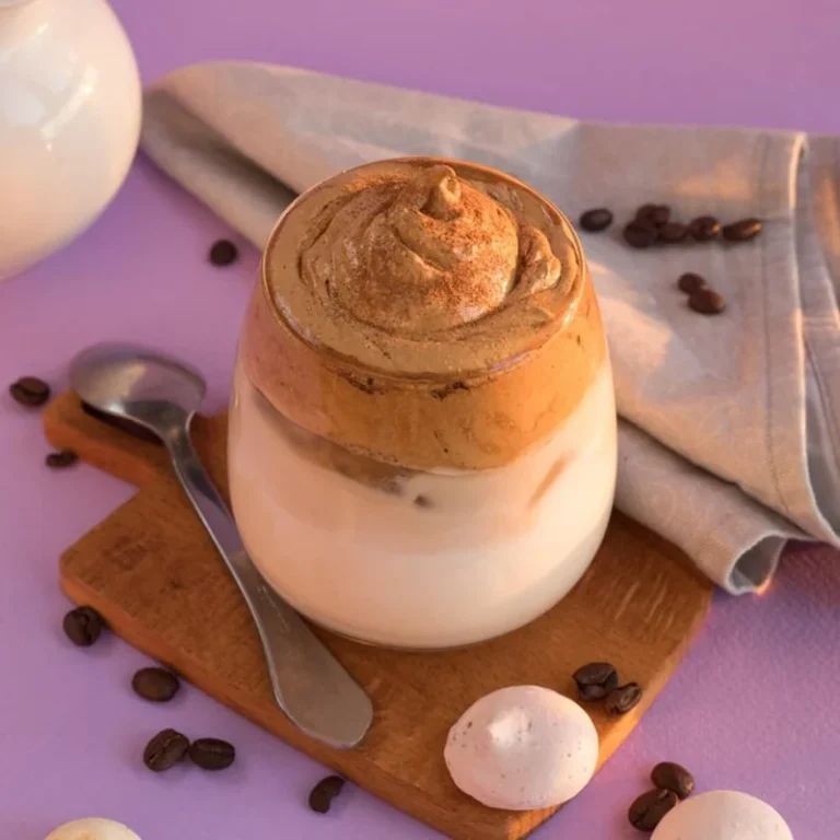 Kawa Dalgona na kolorowej łyżeczce z dzbankiem do mleka i kawą