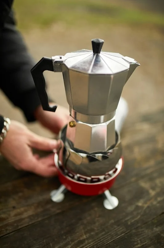 Mężczyzna robi kawę na kempingu z ekspresem na palniku gazowym