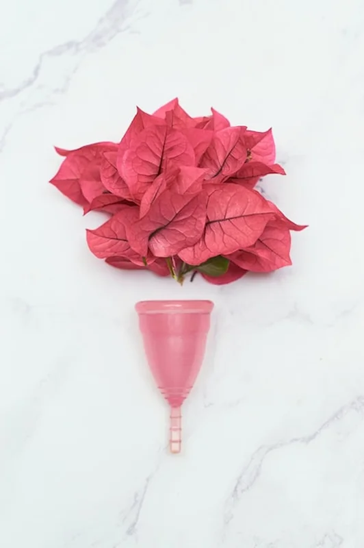 Kubeczek menstruacyjny z kwiatami na marmurowym stole