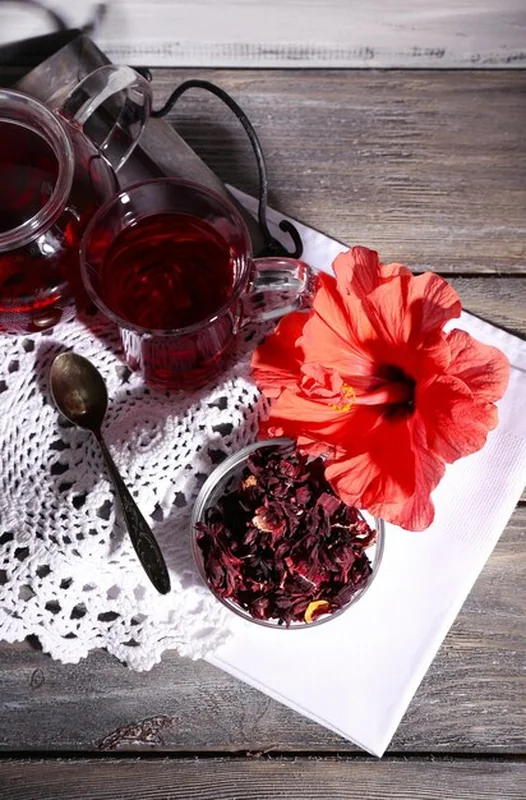 Herbata hibiskusowa w szklanym czajniku na drewnianym tle