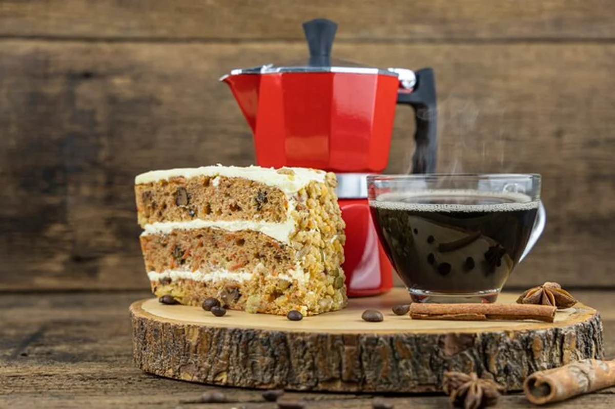 Filiżanka gorącej kawy z ciastem i włoskim dzbankiem na drewnianym stole