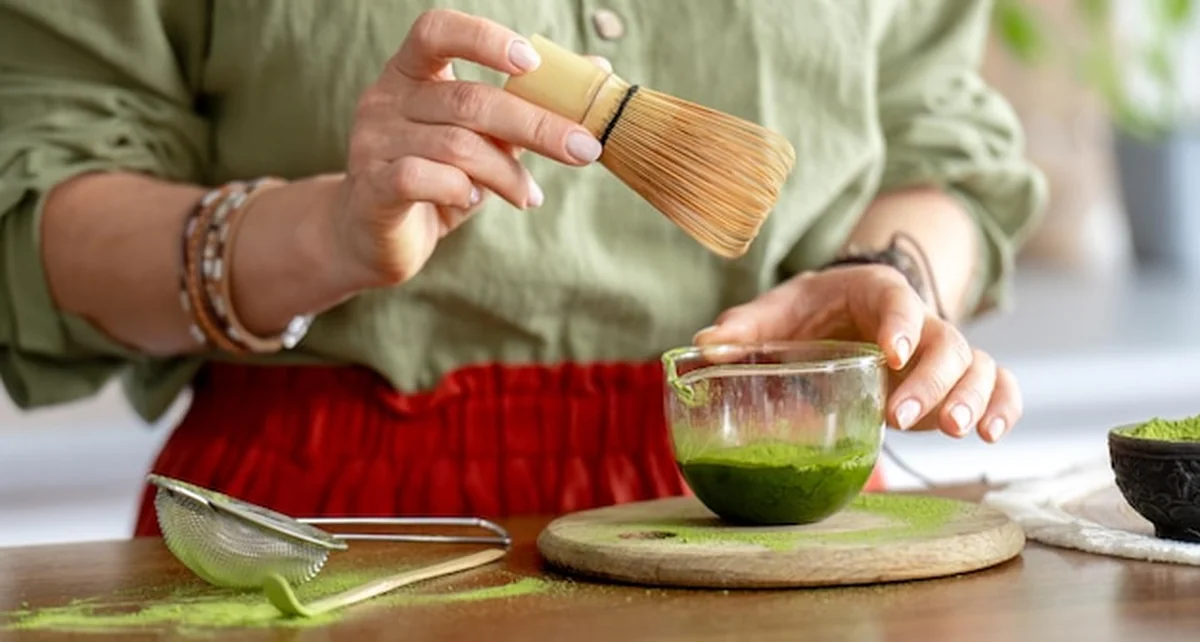 Kobieta mieszająca zieloną herbatę matcha blisko
