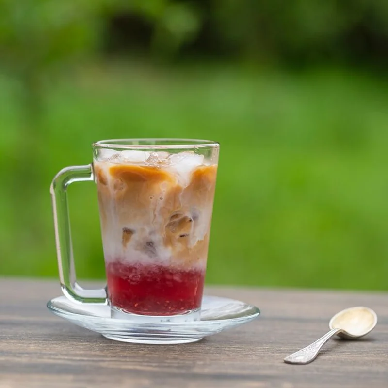 Orzeźwiająca mrożona kawa mleczna z syropem malinowym w letni dzień w ogrodzie