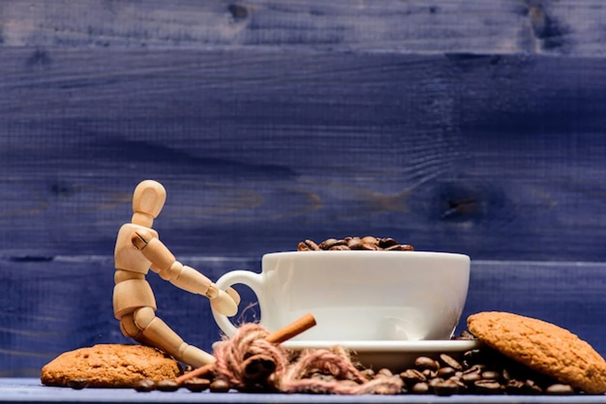 Kubek pełnej kawy i ziarna na drewnianym tle