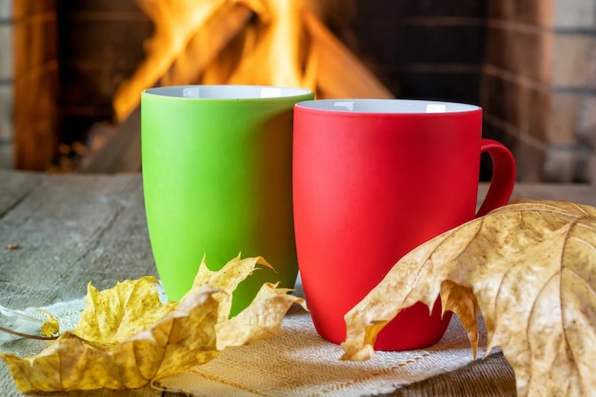 Kubki z napojami i liście przed kominkiem