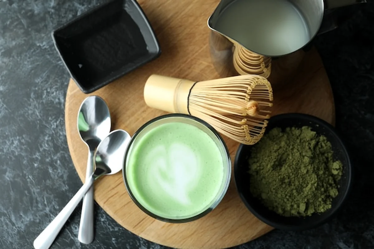 Szklanka matcha latte i akcesoria na czarnym stole
