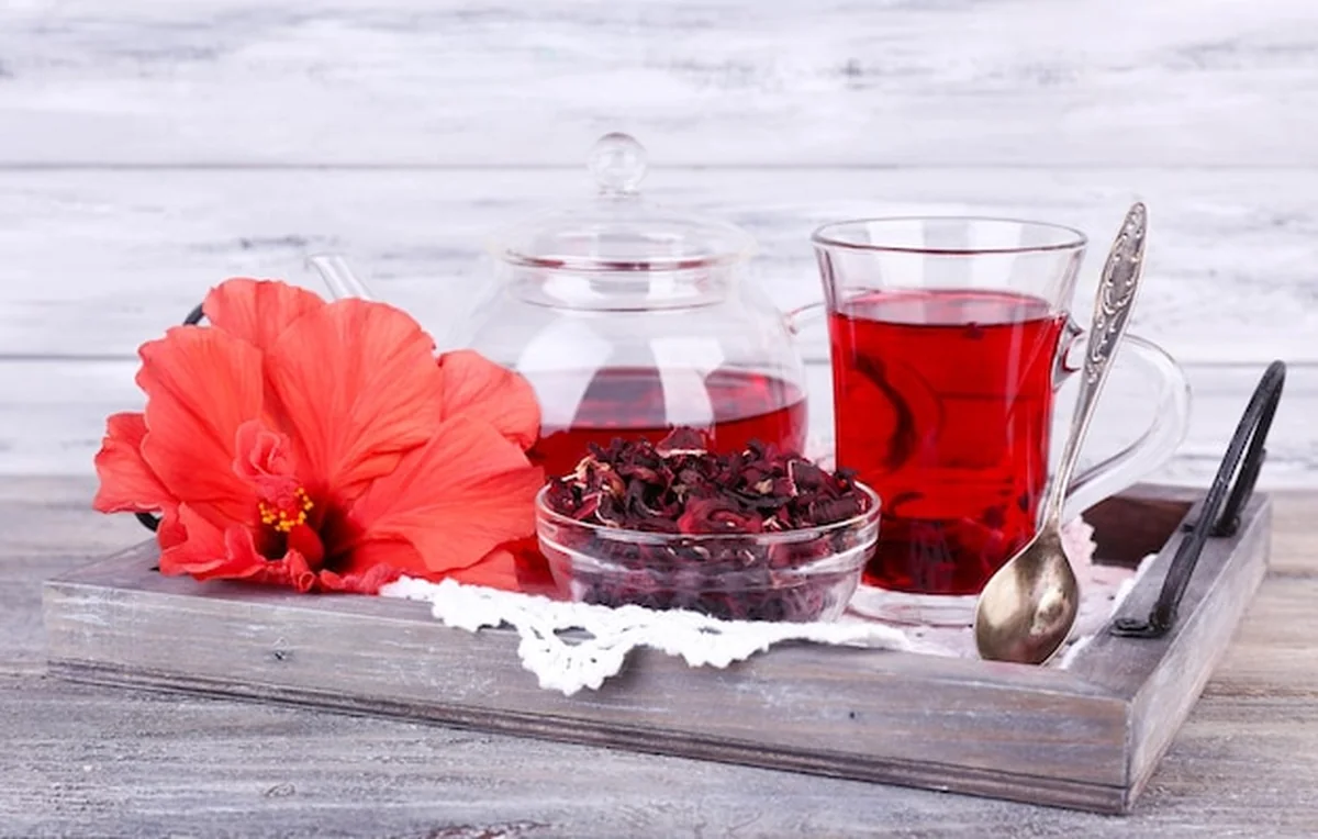 Herbata hibiskusowa w szklanym czajniczku na drewnianym tle