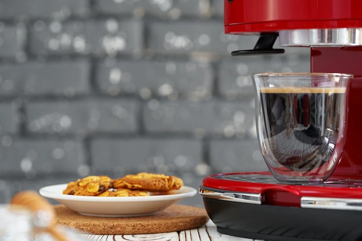 Czerwony ekspres do kawy na blacie kuchennym z szklanką