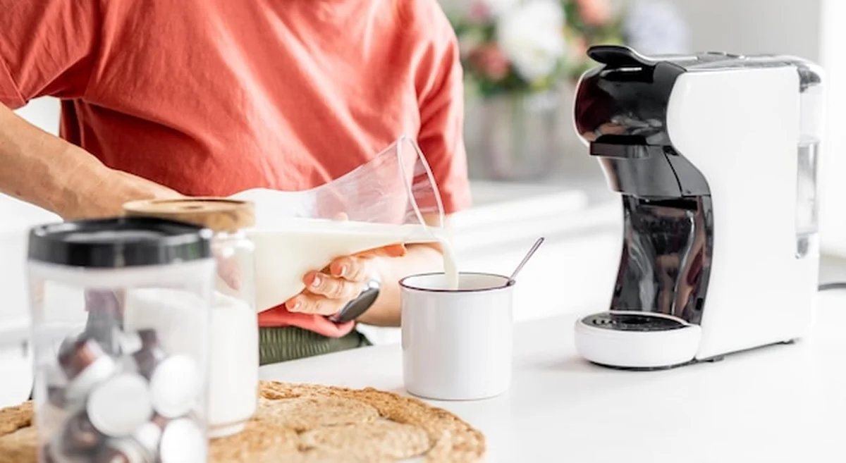 Kobieta dodaje mleko do kawy w domu z bliska